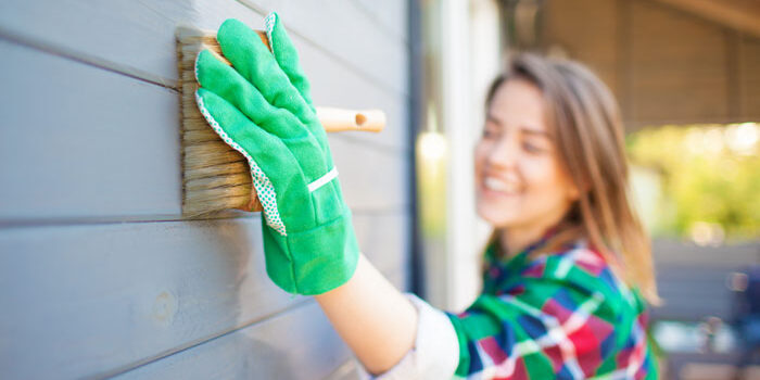 4 Ways to Add Value to Your Home woman painting external siding on her house