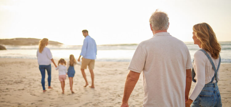 Levels of Estate Planning Family walking together on the beach. What appears to be grandparents are in the foreground watching their kids and grandkids ahead of them.